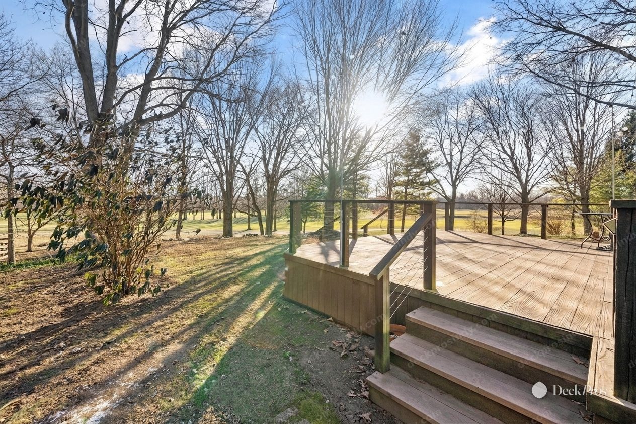 The same deck visualized after rebuilding: fresh decking boards, a stainless cable railing with wood posts, and rebuilt stairs, in the same winter light.
